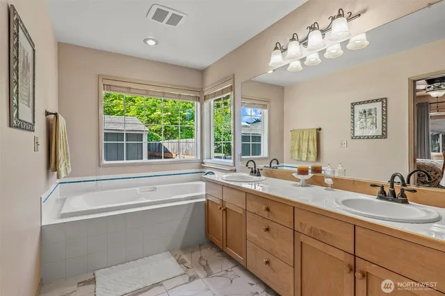 a bathroom with a tub sink double vanity and window