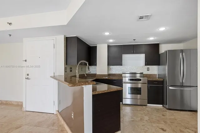 a kitchen with granite countertop a refrigerator stove and sink