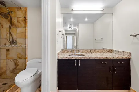 a bathroom with a granite countertop sink toilet and shower