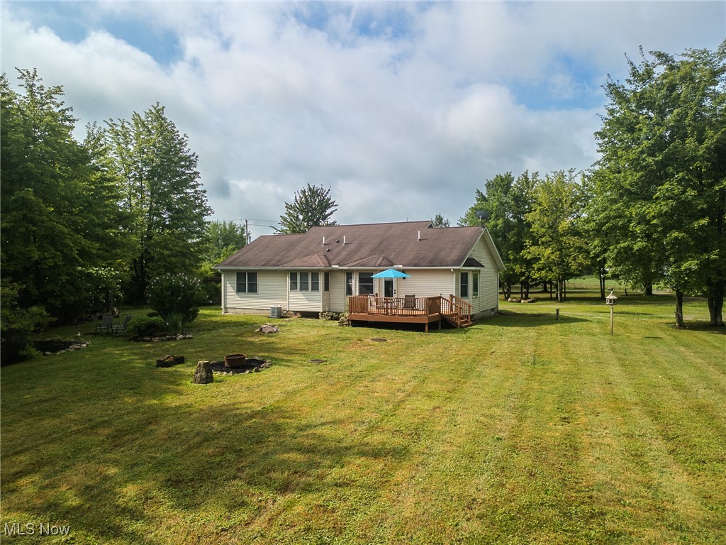 5691 Callahan Road Rome, OH 44085 - Photo 9 of 45 Back of house featuring a wooden deck, a lawn, and an outdoor fire pit