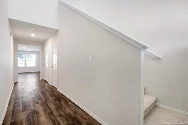 a view of a hallway with wooden floor and a bathroom
