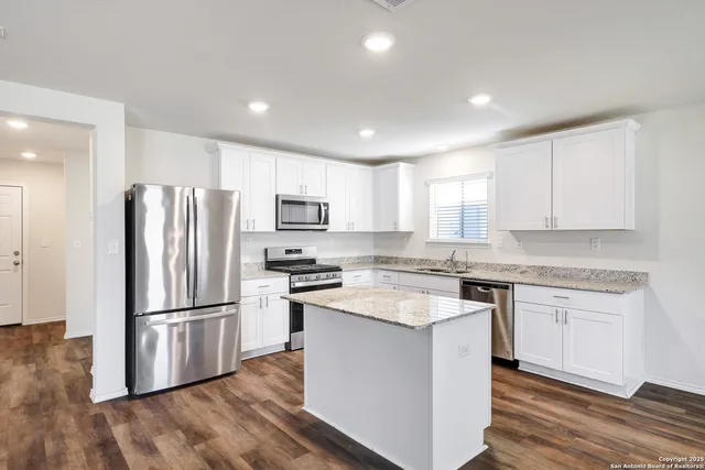 a kitchen with a refrigerator a stove top oven and wooden floor
