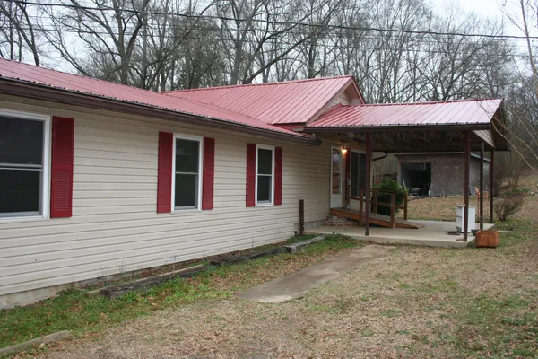 a view of a house with a yard and large tree
