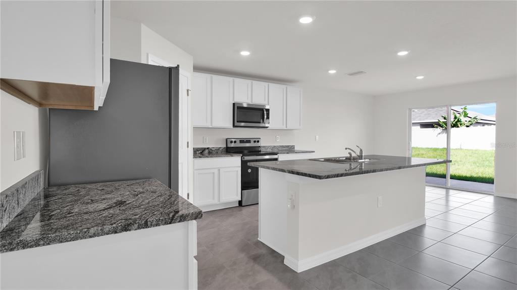 16632 Windmill Forge Pass Wimauma, FL 33598 - Photo 12 of 40 a kitchen with stainless steel appliances granite countertop a sink and a stove