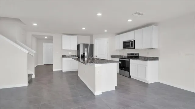 a large kitchen with stainless steel appliances granite countertop a stove a sink and a refrigerator