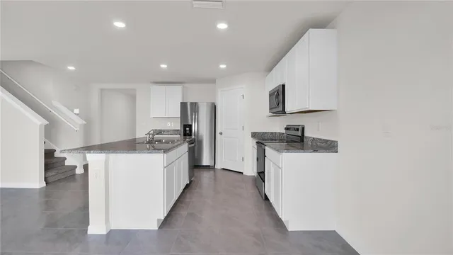 a kitchen with white cabinets and black appliances