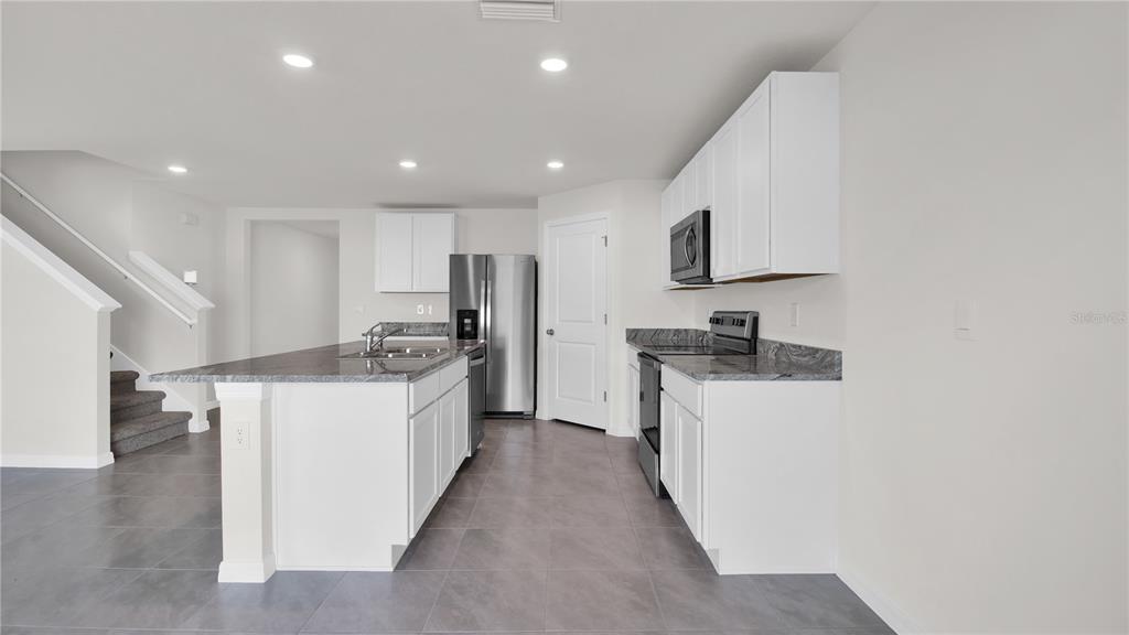 16632 Windmill Forge Pass Wimauma, FL 33598 - Photo 16 of 40 a large kitchen with stainless steel appliances granite countertop a stove a sink and a refrigerator