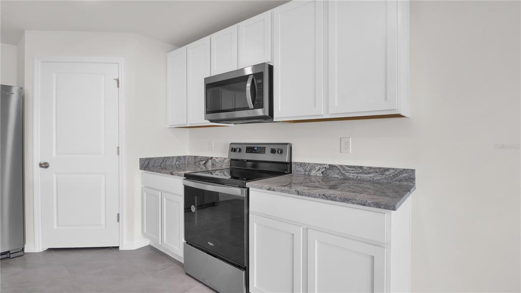 16632 Windmill Forge Pass Wimauma, FL 33598 - Photo 17 of 40 a kitchen with white cabinets and black appliances