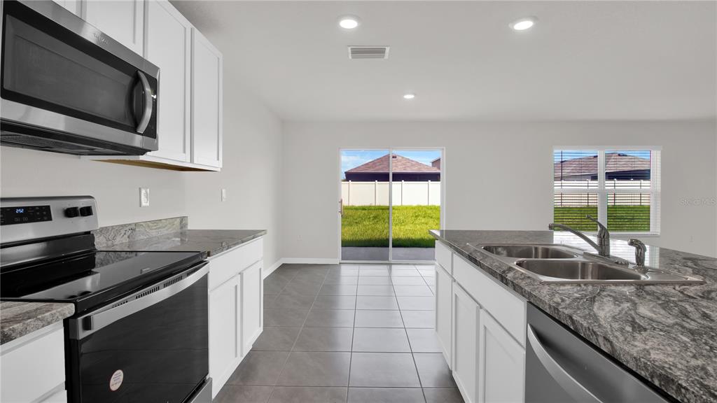 16632 Windmill Forge Pass Wimauma, FL 33598 - Photo 20 of 40 a kitchen with stainless steel appliances granite countertop a sink a stove and a microwave