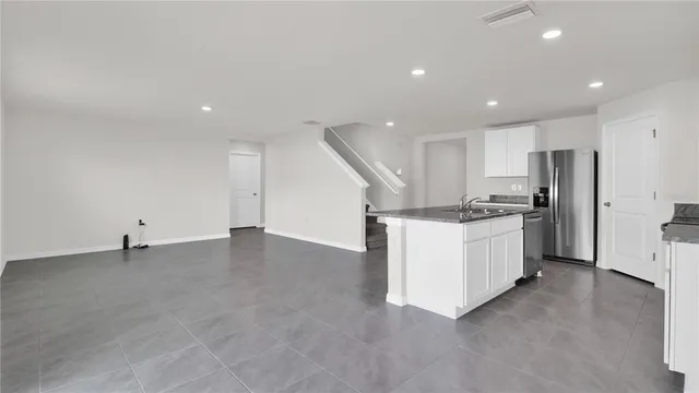 a view of an empty room with a window and kitchen view