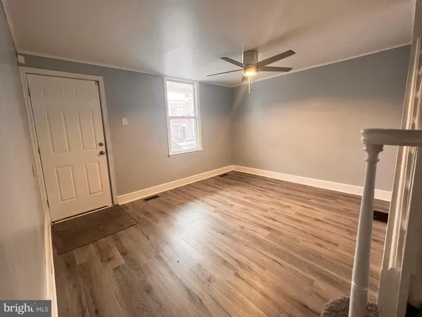 a view of empty room with wooden floor and fan