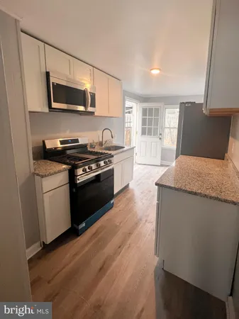 a kitchen with granite countertop wooden floors and stainless steel appliances