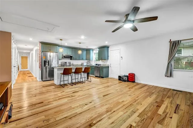 a living room with stainless steel appliances kitchen island furniture and a wooden floor