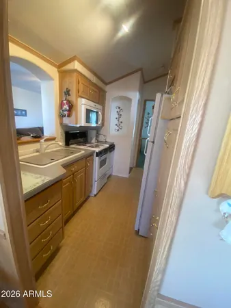 a kitchen with a sink a stove top oven a refrigerator and a window