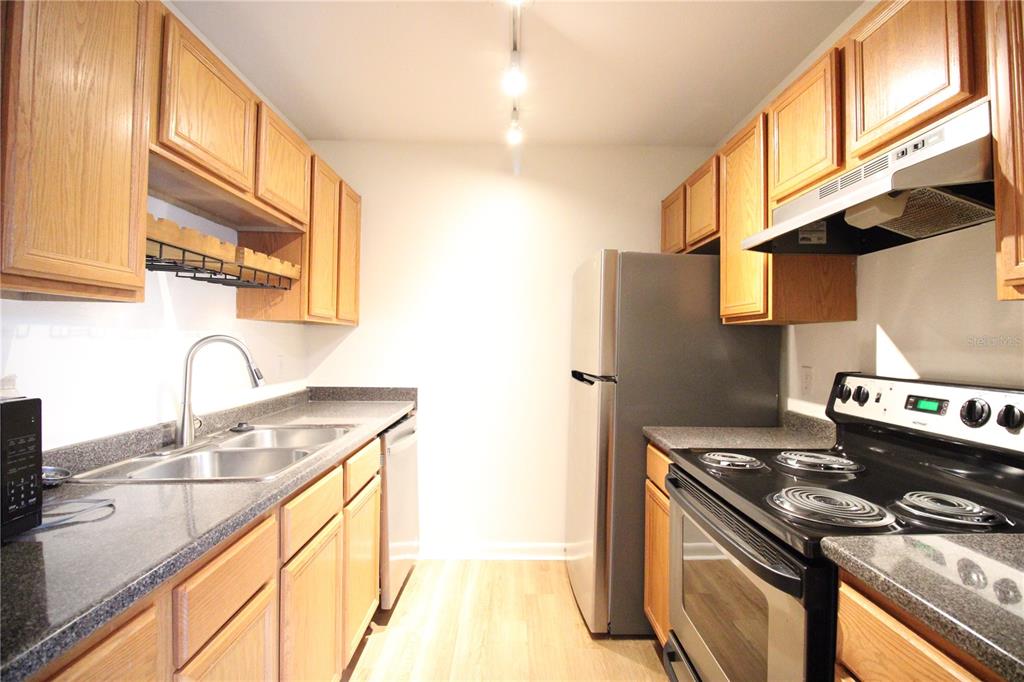 507 Northwest 39th Road, Unit 112 Gainesville, FL 32607 - Photo 7 of 23 a kitchen with stainless steel appliances granite countertop a sink a stove and a wooden cabinets