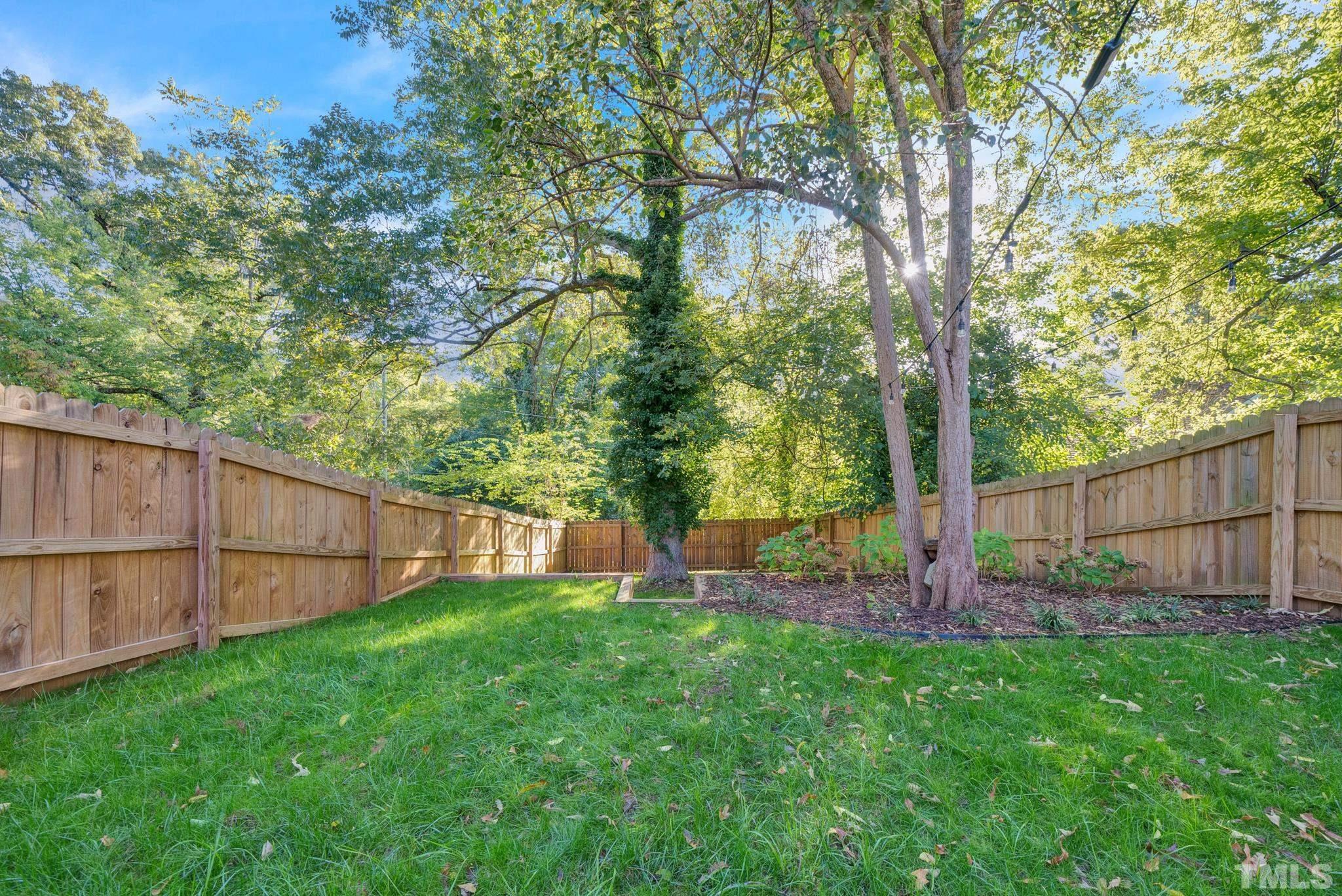 107 Bart Street Raleigh, NC 27610 - Photo 18 of 20 a view of a backyard with a large tree and wooden fence