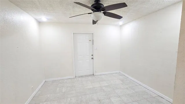 an empty room with a ceiling fan and carpet