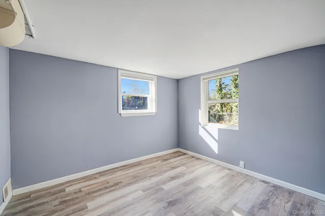 a view of empty room with window and wooden floor