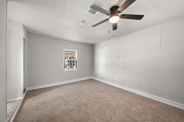 an empty room with a window and a fan