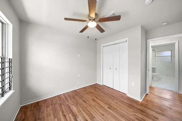a view of empty room with wooden floor and ceiling fan