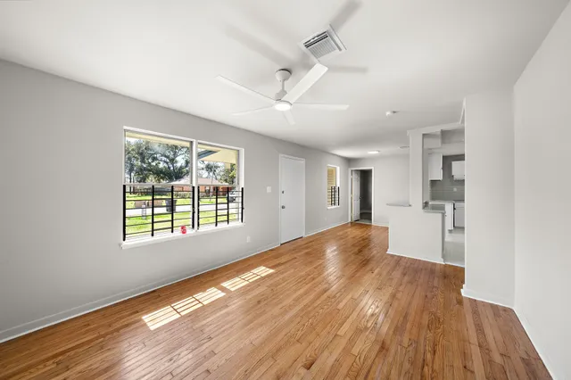 a view of empty room with wooden floor and fan