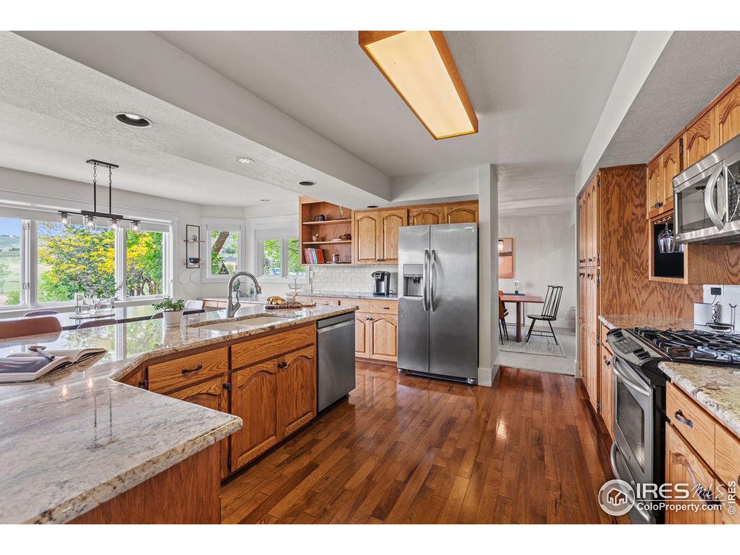 2213 Grosvenor Court Fort Collins, CO 80526 - Photo 12 of 40 a kitchen with stainless steel appliances granite countertop a refrigerator a sink dishwasher a stove and white countertops with wooden floor