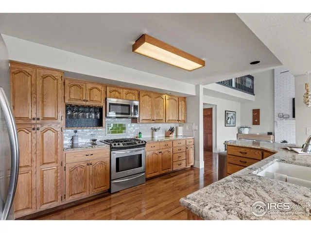 a kitchen with stainless steel appliances granite countertop a stove top oven a sink dishwasher a dining table and chairs with wooden floor