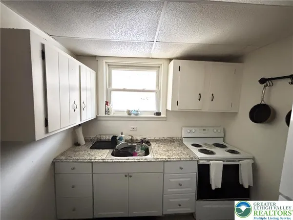 a kitchen with a sink a stove cabinets and a window