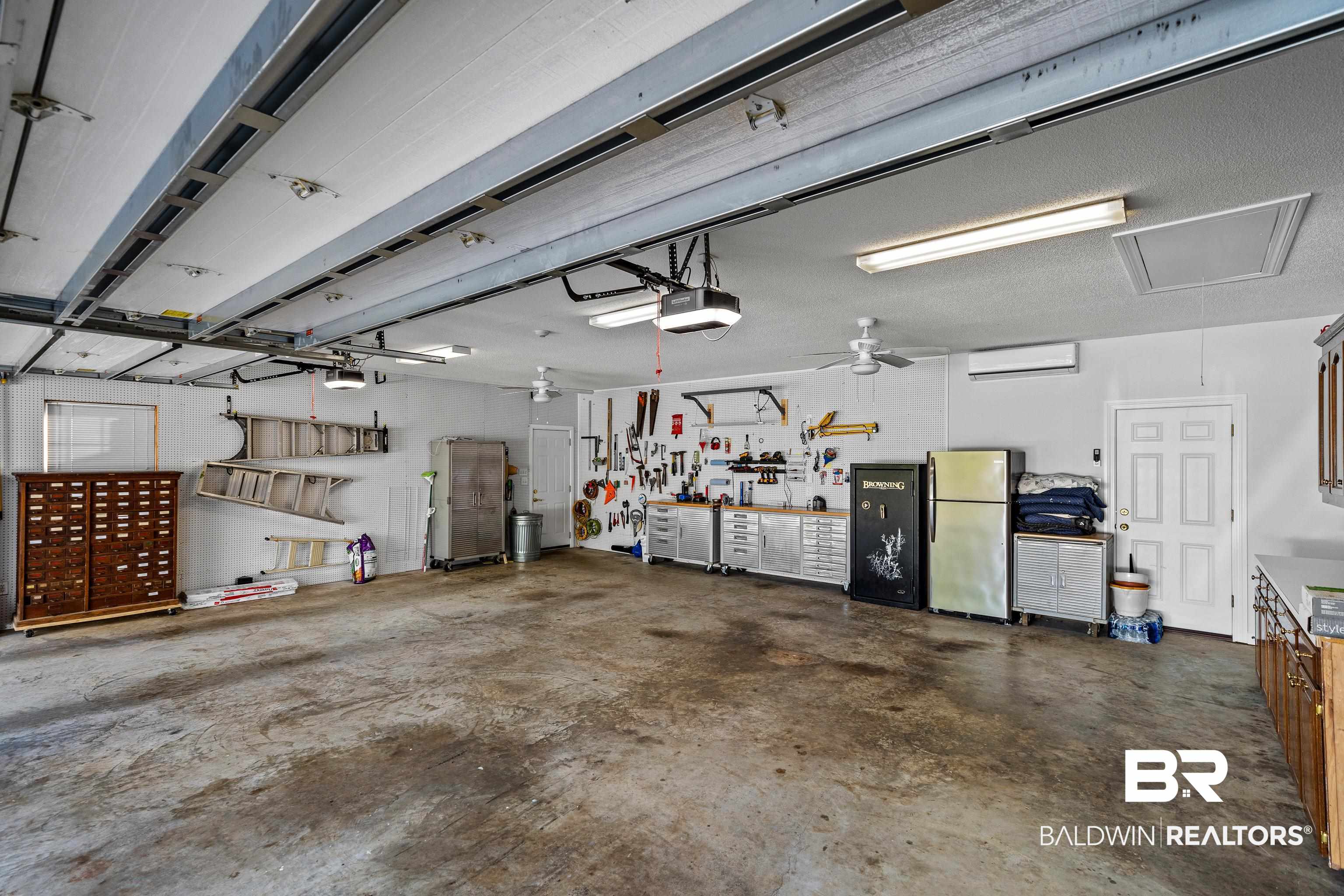 31267 Blakeley Ridge Court Spanish Fort, AL 36527 - Photo 56 of 61 Garage featuring a garage door opener, freestanding refrigerator, and a workshop area