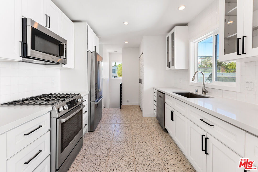 1253 South Rimpau Boulevard Los Angeles, CA 90019 - Photo 12 of 71 a kitchen with stainless steel appliances a sink a stove and a refrigerator