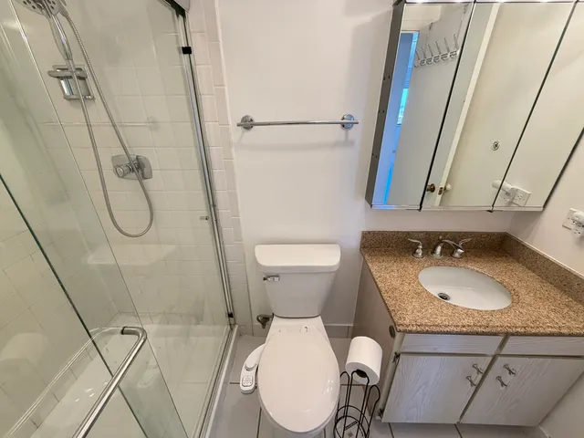 a bathroom with a granite countertop toilet sink and mirror