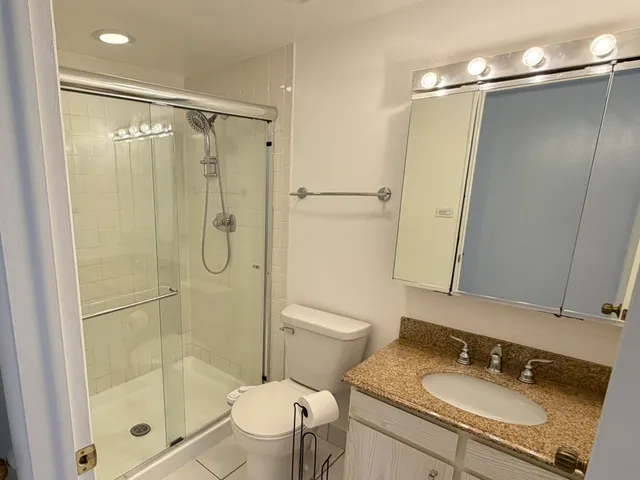 a bathroom with a granite countertop sink toilet and shower