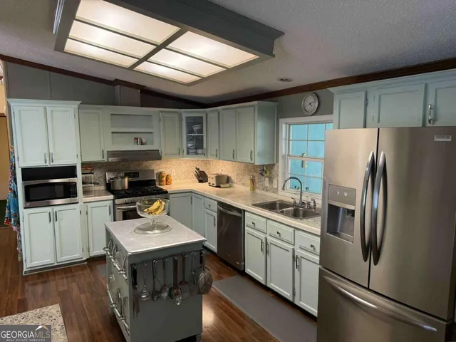 a kitchen with stainless steel appliances a refrigerator a sink a stove a microwave and wooden cabinets