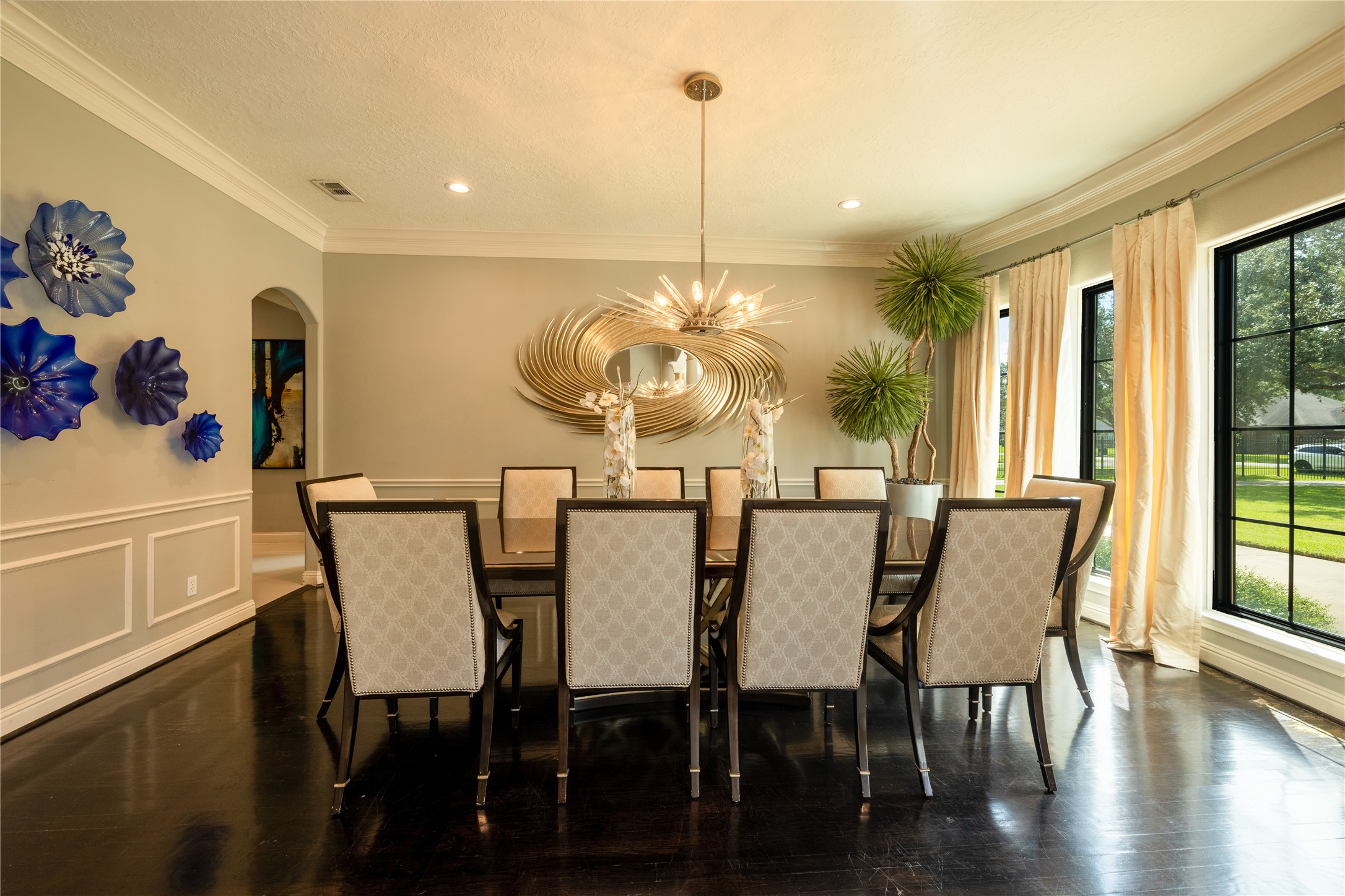 4002 Silver Ridge Boulevard Missouri City, TX 77459 - Photo 9 of 50 This is an elegant dining room featuring a large table with ten chairs, hardwood floors, decorative wall art, modern lighting, and ample natural light from large windows with a view of a well-maintained lawn.