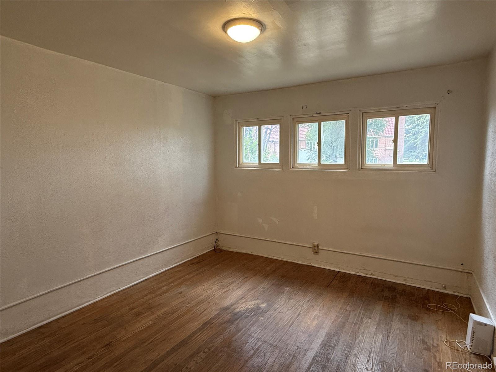 134 West 3rd Street Center, CO 81125 - Photo 8 of 13 an empty room with wooden floor and windows
