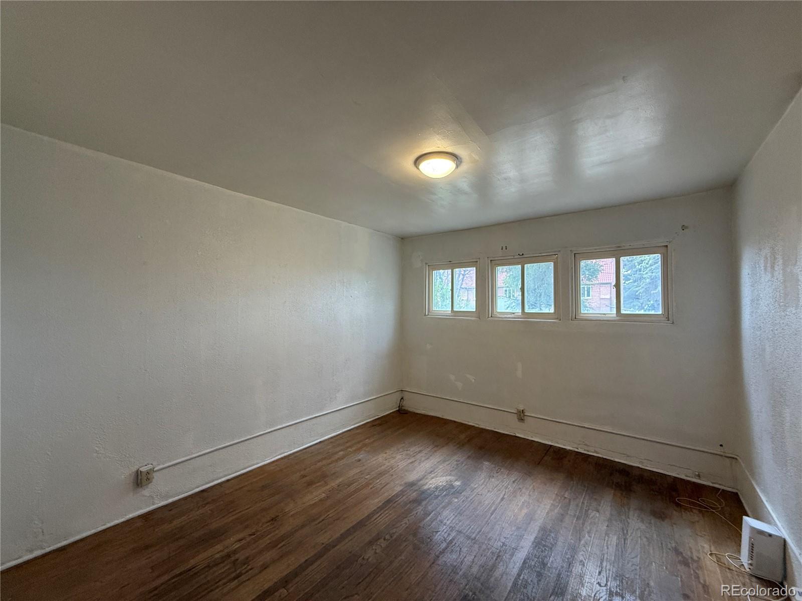 134 West 3rd Street Center, CO 81125 - Photo 10 of 13 an empty room with wooden floor and windows