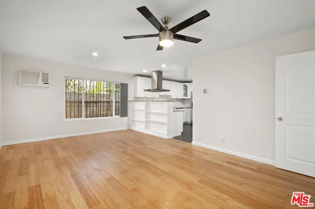 a view of a kitchen with wooden floor a ceiling fan and windows