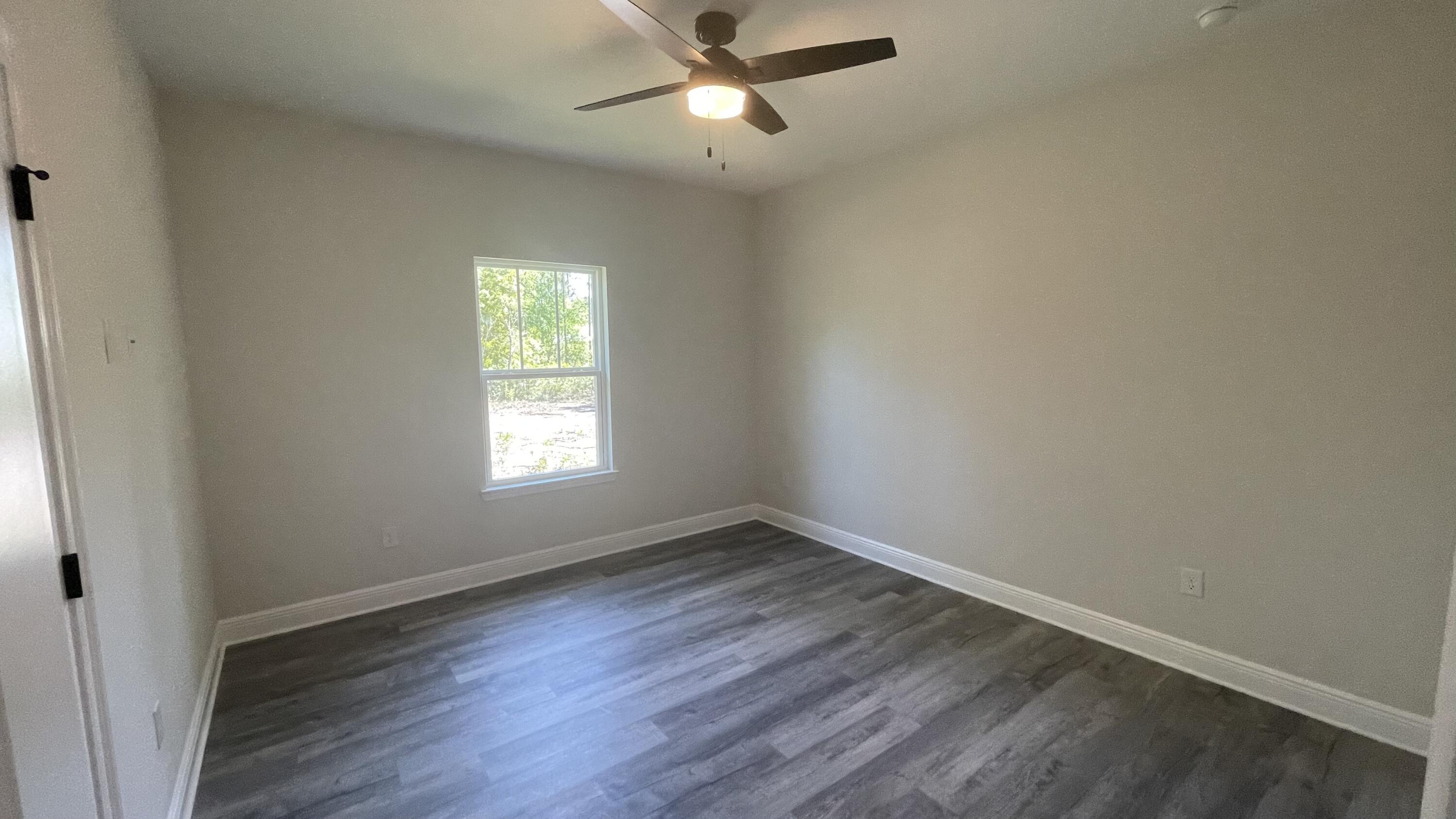 116 Bear Creek Boulevard Freeport, FL 32439 - Photo 12 of 16 an empty room with wooden floor ceiling fan and windows