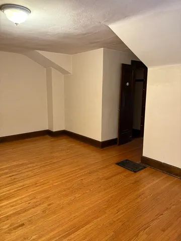 a view of an empty room with wooden floor and closet