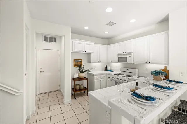 a kitchen with stainless steel appliances kitchen island granite countertop a sink stove and white cabinets