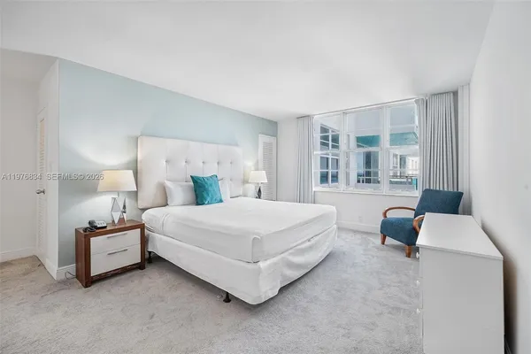 a bedroom with a bed lamp and a large window
