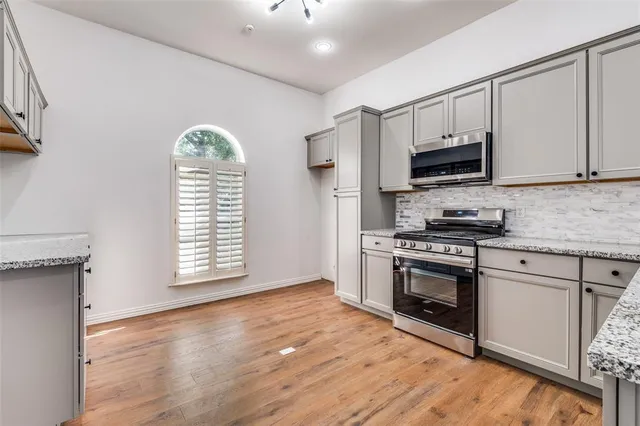 a kitchen with stainless steel appliances granite countertop a stove a sink and a microwave