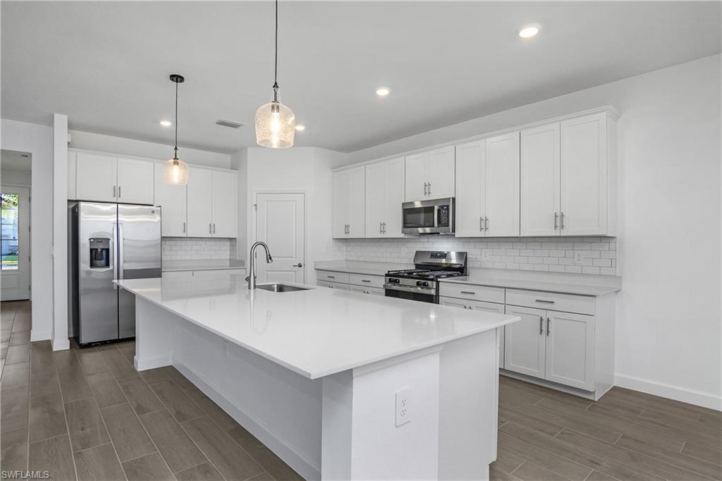 21140 Verawood Loop Estero, FL 33928 - Photo 4 of 50 Kitchen features natural gas appliances, oversized island, quartz countertops, over and under cabinet lighting, and walk-in pantry.