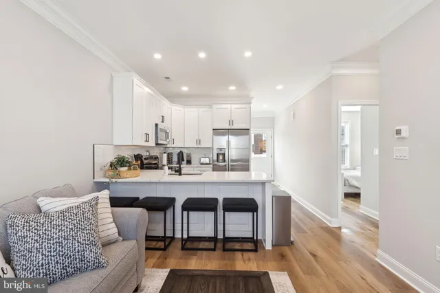 a living room with furniture a wooden floor and kitchen view