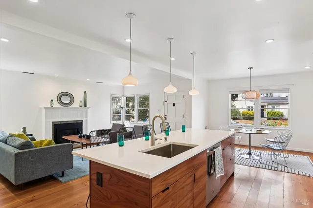 a open kitchen with stainless steel appliances granite countertop a stove oven a dining table and chairs with wooden floor