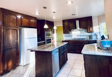 a kitchen with stainless steel appliances granite countertop a refrigerator a sink and a stove