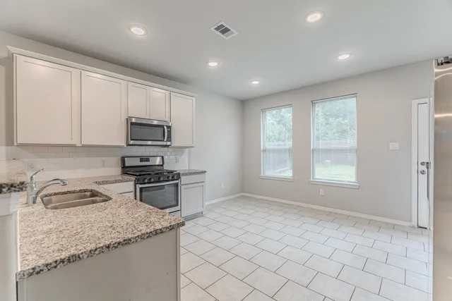 a kitchen with sink a microwave and cabinets