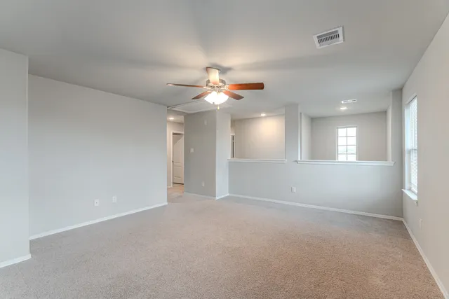 a view of an empty room with a ceiling fan and window
