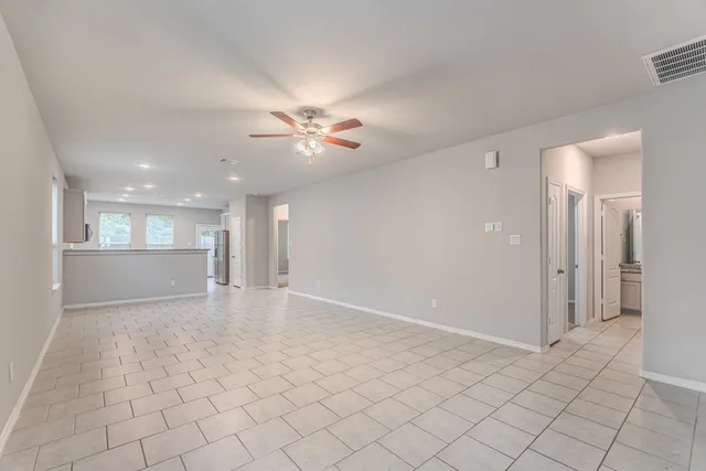 a view of an empty room and a kitchen