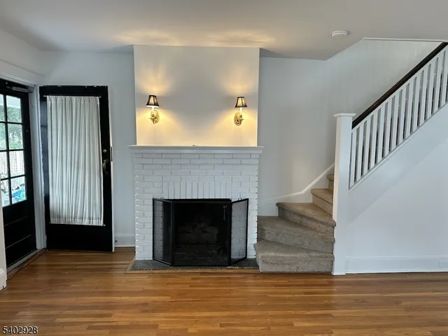 a view of a livingroom with a fireplace wooden floor and staircase